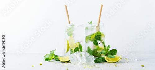 Close up of two glasses with tropical mojito cocktail on light background with copy space. Summer time vacation concept. photo