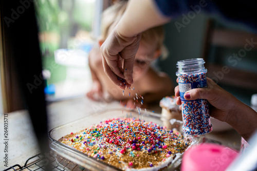 Young child decorating fresh cake with lots of sprinkles photo