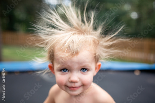 Toddler girl on trampoline with wild static hair