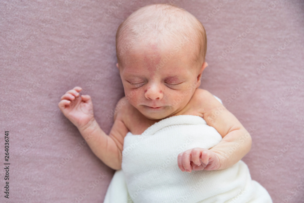 Close up Newborn Baby Girl in White Wrap Laying on Pink Blanket Close up Newborn Baby Girl in White Wrap Laying on Pink Blanket