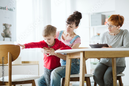 Fotografía Bad behaving cute boy trying to run during therapy session with his mother and t