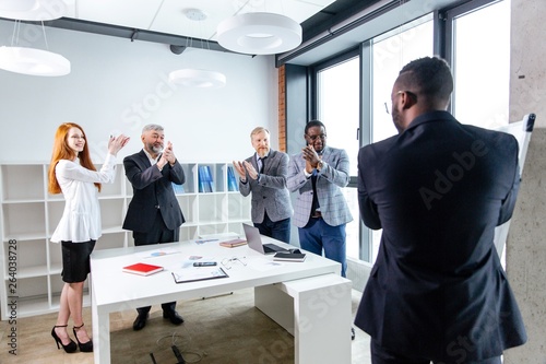African man with glasses holds a press conference among business partners. Colleagues applaud the successful performance