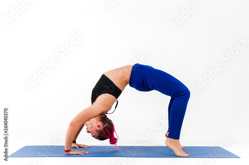 Girl standing in bridge pose doing yoga on white background