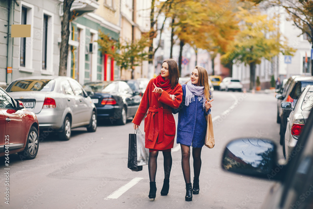 two beautiful and stylish girlfriends walking around the spring city with packages and shopping