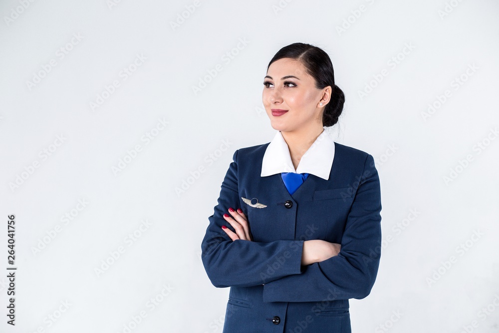 Portrait of a flight attendant in a blue uniform with her arms crossed in front of her standing on a white background Portrait of a flight attendant in a blue uniform with her arms crossed in front of her standing on a white background