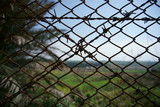 Closeup view of chain link and barbed fence with blurred background