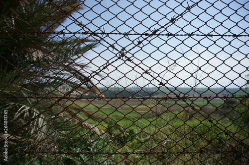 Closeup view of chain link and barbed fence with blurred background