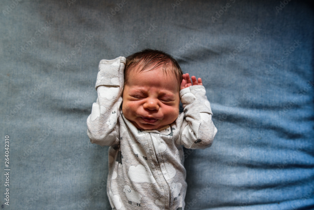 newborn laying down and making funny face with hands up newborn laying down and making funny face with hands up