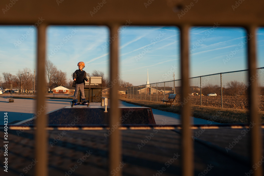 Looking through rails at boy at skate park on top of ramp Looking through rails at boy at skate park on top of ramp