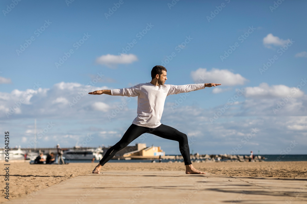Man doing Yoga on the beach in Barcelona Man doing Yoga on the beach in Barcelona