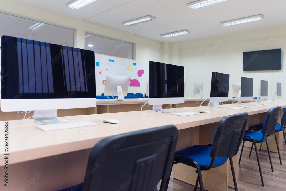 Modern office with computers on desks. Empty computer room in college. Interior of classroom with computers. Concept of corporate working space. Modern office with computers on desks. Empty computer room in college. Interior of classroom with computers. Concept of corporate working space.