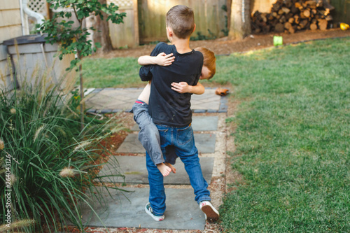 a young boy carries his little brother in his arms