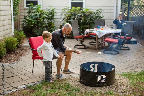A father roasts marshmallows with his children in yard photo