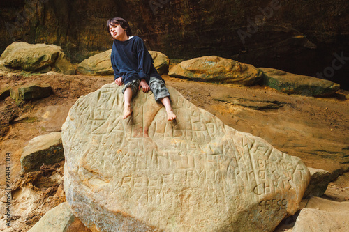 Portrait of a small boy sitting on a large rock in a sandstone gorge