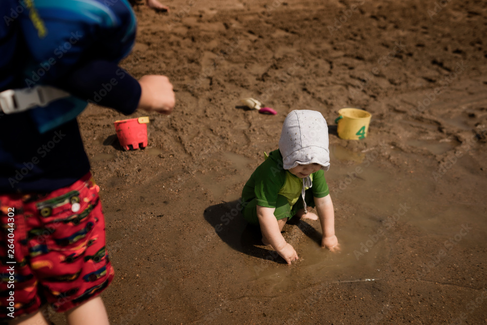 Little girl in bonnet playing with brother at the beach Little girl in bonnet playing with brother at the beach