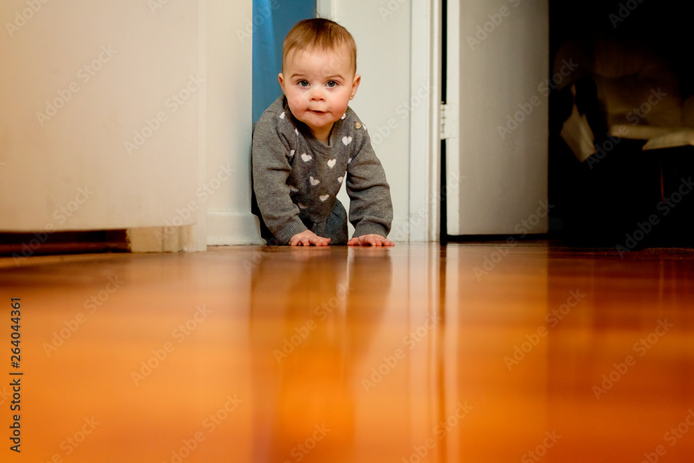 A baby girl crawling on the floor past a door way A baby girl crawling on the floor past a door way