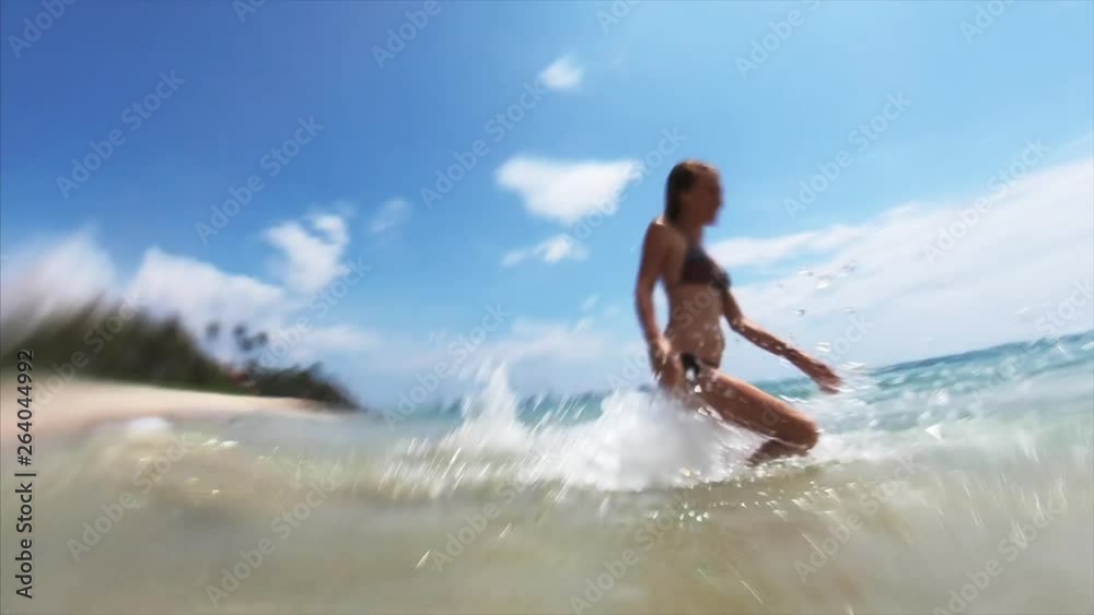 Young happy woman run into the sea with lot of splashes and jump over the breaking wave Young happy woman run into the sea with lot of splashes and jump over the breaking wave