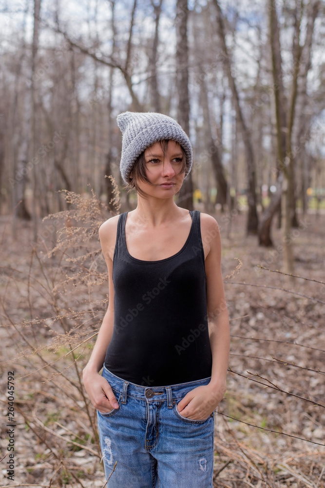 A young woman wearing a t-shirt and hat is standing in the forest. A young woman wearing a t-shirt and hat is standing in the forest.