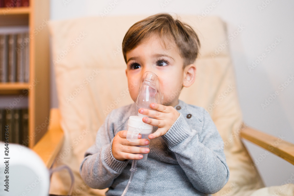 Little boy using steam inhaler nebulizer mask inhalation at home. Medical procedures vapor medication treatment asthma pneumonia bronchitis coughing Little boy using steam inhaler nebulizer mask inhalation at home. Medical procedures vapor medication treatment asthma pneumonia bronchitis coughing