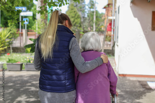 Young carer walking with the elderly woman in the garden