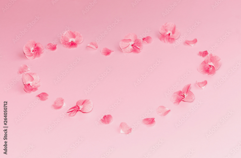 Composition of pink flowers in a shape of heart on pastel pink background. Copy space.