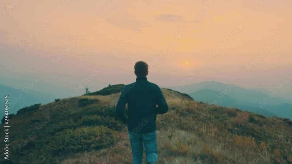 The man running on the mountain against the sunset background. slow motion