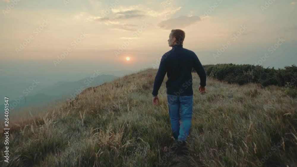 The man walking on the mountain against the sunset background. slow motion The man walking on the mountain against the sunset background. slow motion