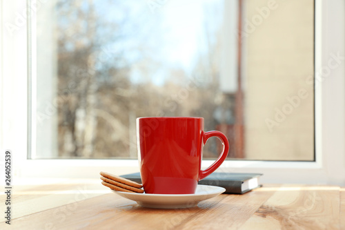 Cup of hot winter drink and cookies on wooden windowsill, space for text