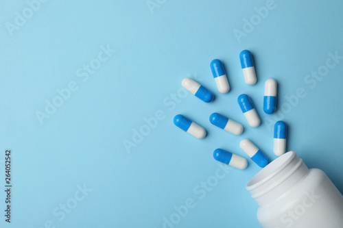 Bottle with pills on color background, flat lay. Space for text