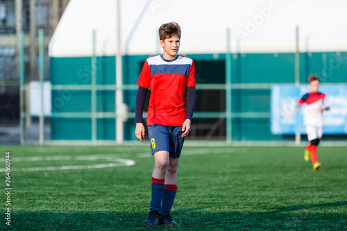 Boys at white red sportswear run, dribble, attack on football field. Young Soccer players with ball on green grass. Training, football, active lifestyle for kids   © Natali