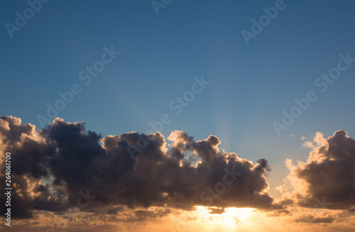 Sunrise with blue sky and sun behind the clouds