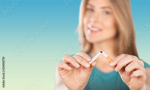 Young woman breaking cigarette on background