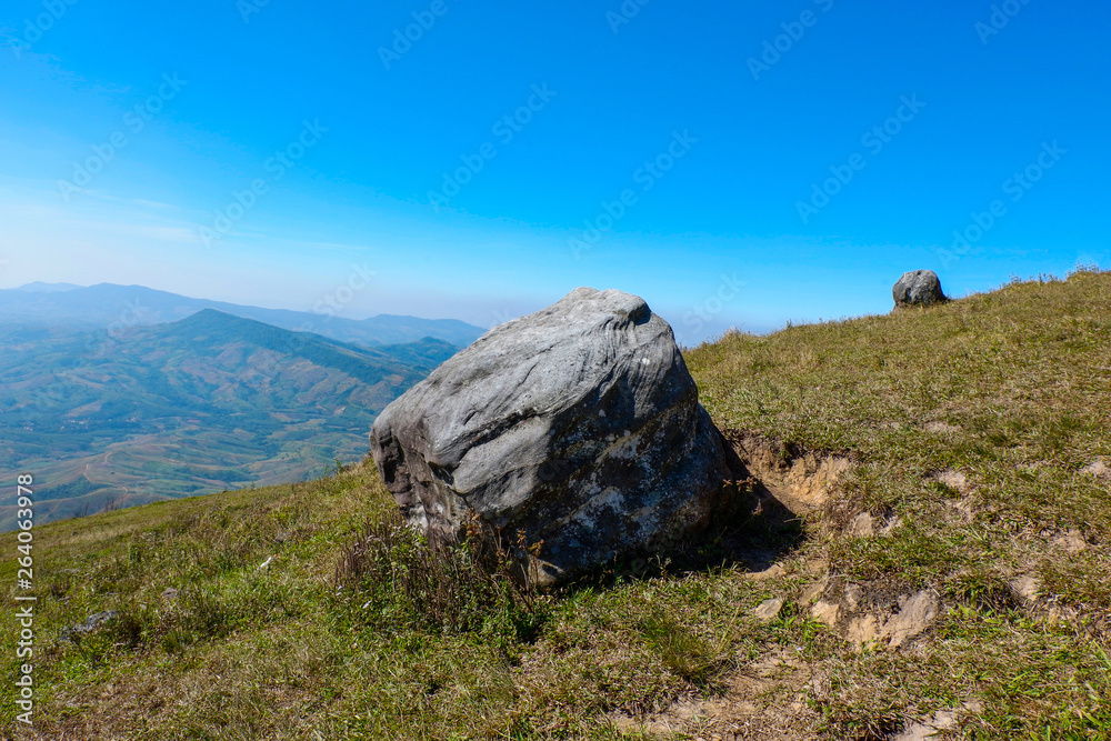 Rock on hill with mountain and blue sky background / Landscape stone field