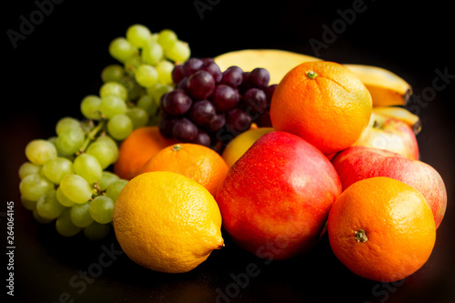 Beautiful juicy fruits on a black background  apples  grapes  oranges  bananas  close-up