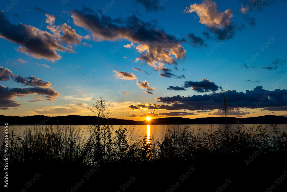 Dramatic cloud formations and blue sky above the Hudson River, as the sun sets behind the hills, Upstate New York, NY Dramatic cloud formations and blue sky above the Hudson River, as the sun sets behind the hills, Upstate New York, NY