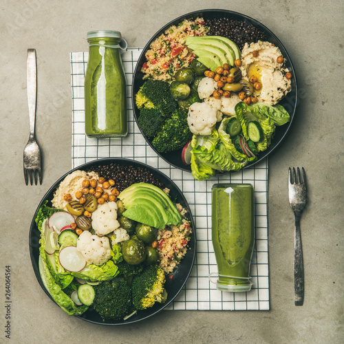 Healthy dinner, lunch setting. Flat-lay of vegan superbowls or Buddha bowls with hummus, vegetables, fresh salad, beans, couscous and avocado and green smoothies in bootles, top view, square crop photo