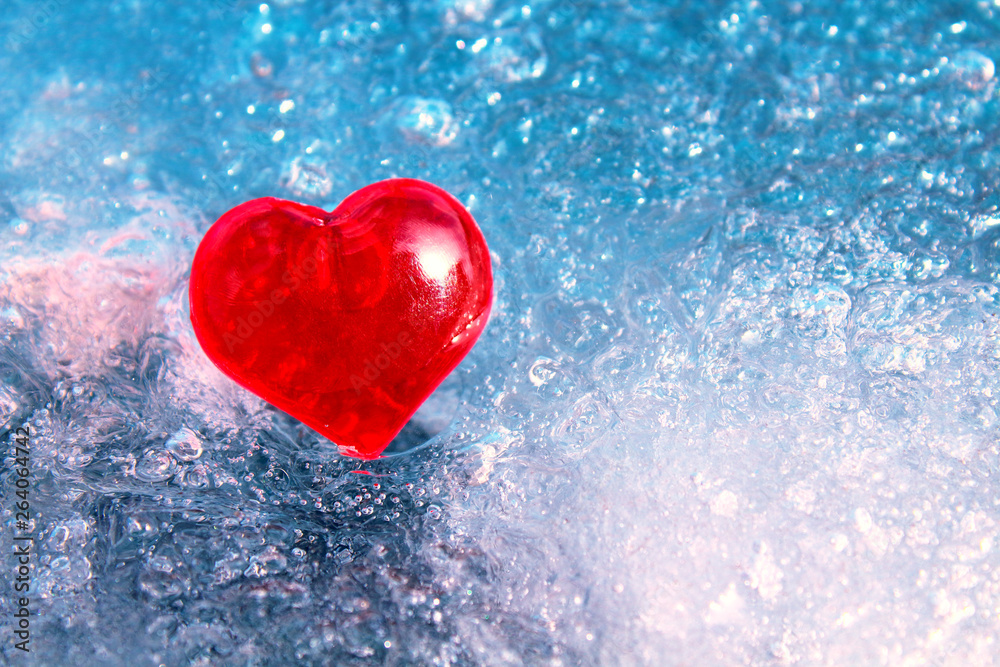 Red glass heart on ice. Close-up. Background. Texture.