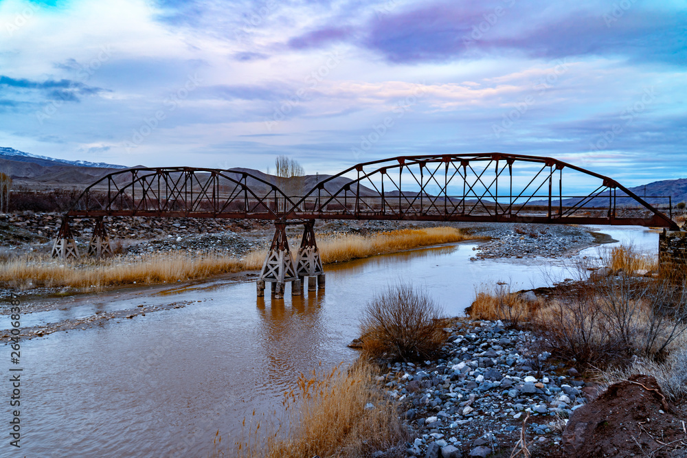 A view of brilliant river and mountains with eye-catching steel bridge.