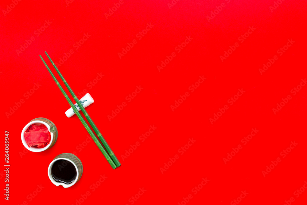 asian cuisine set with bamboo sticks, soy sauce and ginger for sushi and maki on red background top view mock up asian cuisine set with bamboo sticks, soy sauce and ginger for sushi and maki on red background top view mock up