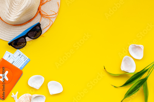 Summer travaling to the sea with straw hat, sun glasses, tickets and passport on yellow background top view mock up