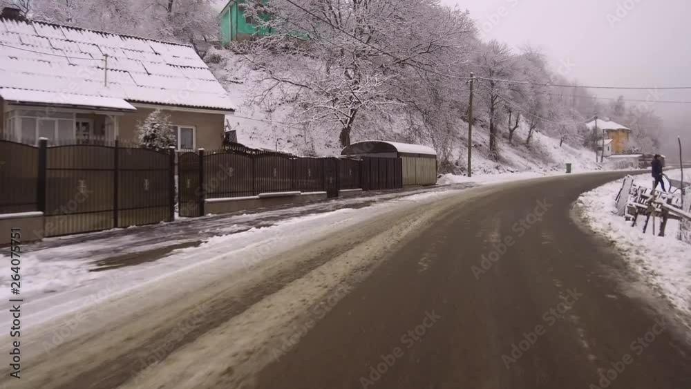 Snowy, dangerous driving on a narrow road leading to Colibita, Romania while winding through a quaint mountain village. Winter landscape scenery. Snowy, dangerous driving on a narrow road leading to Colibita, Romania while winding through a quaint mountain village. Winter landscape scenery.