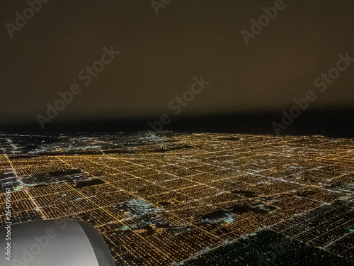 View of Chicago's illuminated city night lights seen through the window of an airplane