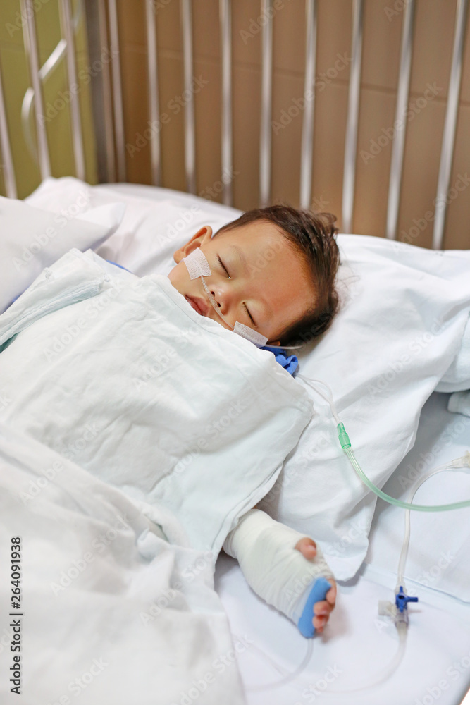 Baby boy with breathing tube in nose receiving medical treatment. Intensive care and attaching intravenous tube to hand on bed at hospital. Respiratory Syncytial Virus (RSV). Baby boy with breathing tube in nose receiving medical treatment. Intensive care and attaching intravenous tube to hand on bed at hospital. Respiratory Syncytial Virus (RSV).