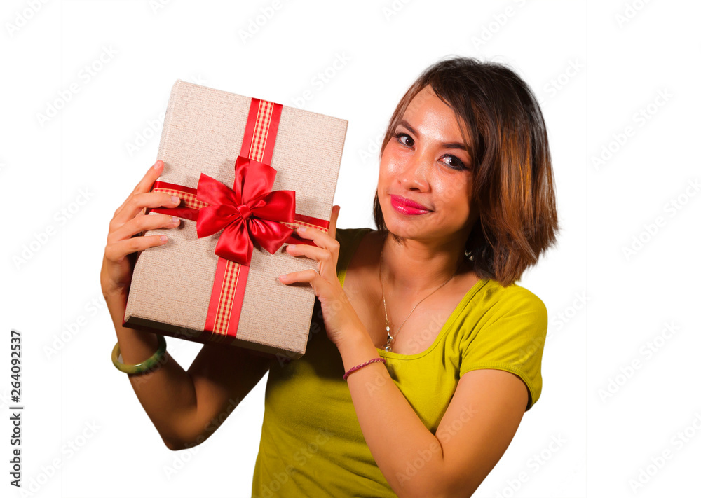 portrait of young happy and beautiful Asian Indonesian woman holding Christmas present or birthday gift box with red ribbon excited and cheerful smiling isolated portrait of young happy and beautiful Asian Indonesian woman holding Christmas present or birthday gift box with red ribbon excited and cheerful smiling isolated