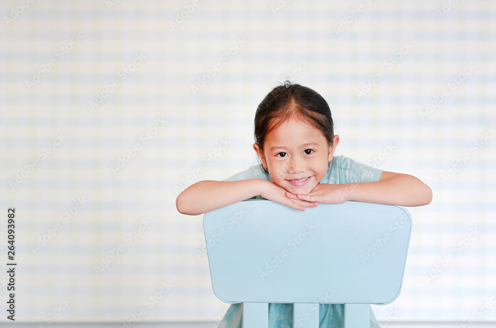 Happy Asian child preschool girl in a Kindergarten room poses on plastic baby chair. Happy Asian child preschool girl in a Kindergarten room poses on plastic baby chair.