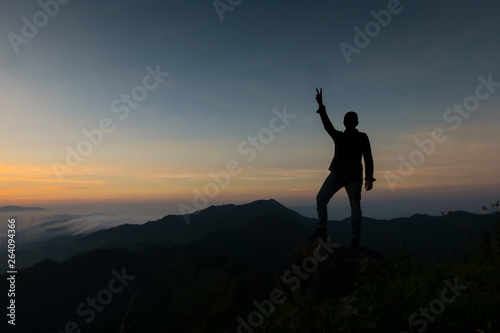 Handsome young man Standing behind two fingers to show the strength to continue fighting. photo style silhouette and low key.