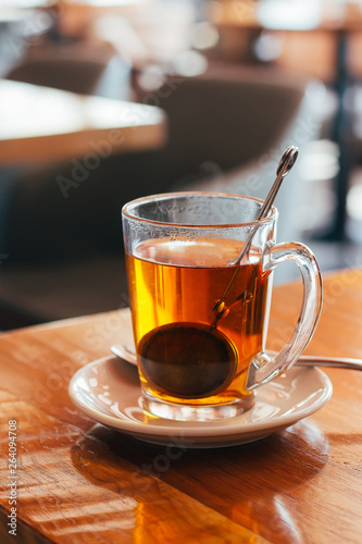 Glass Mug of hot tea at a cafe with blurred background. Natural light