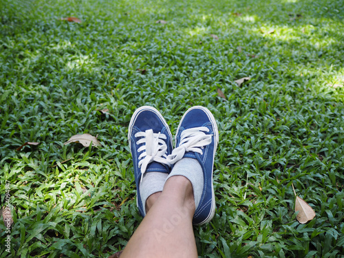 Selfie feet wearing blue sneaker on green grass in the park.