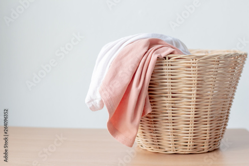 white and pink clothes in laundry basket with copy space on table..