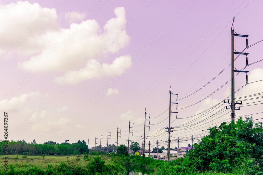 Row of electricity pole on green nature road in Thailand, Transmission line of electricity to rural, High voltage electricity pole on bright sky clouds background, electricity transmission pylon